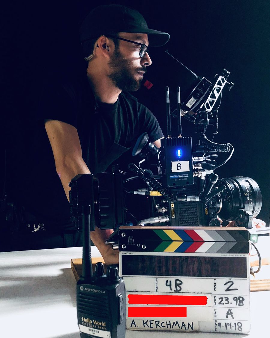 Adam Kerchman on set, behind the camera with a slate in front