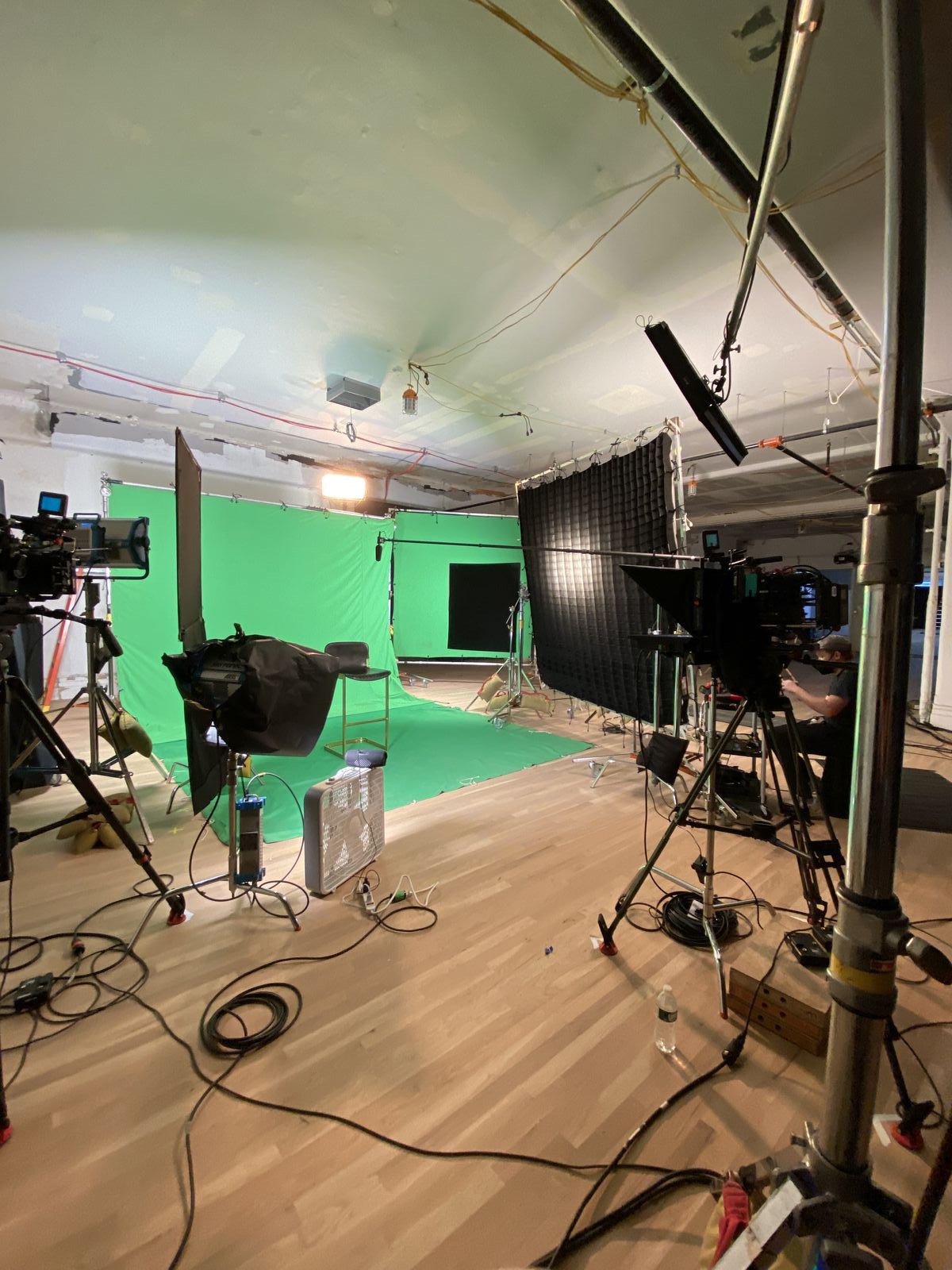 wide of the green screen setup with cameras and lighting