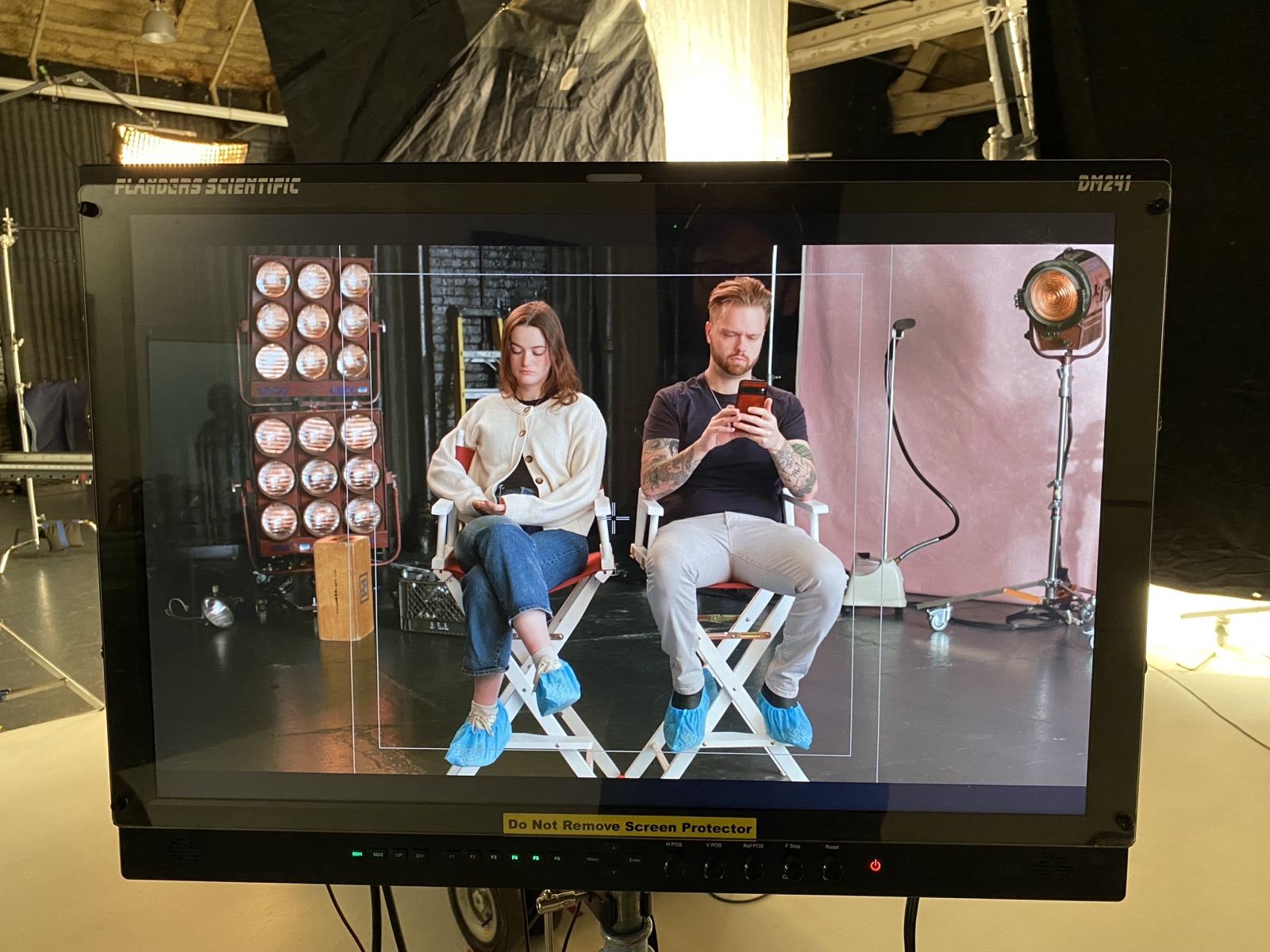 Stand-ins in booties on the monitor, frame lines up for the two-shot